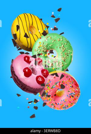 Sweet donuts, chocolate crumbs and sprinkles falling on blue background Stock Photo