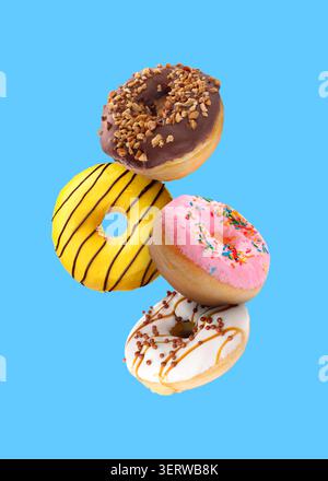 Tasty donuts covered with icing falling on blue background Stock Photo