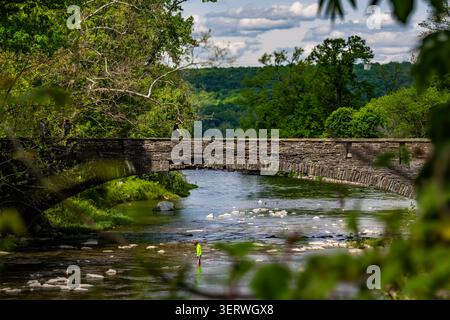 Ulysses, NY, USA - May 31, 2026:  Photo of Route 89 stone bridge on spring day, with hiker, crossing, Taughannock Creek.  Taughannock Falls State Park Stock Photo