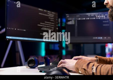 Programmer typing lines of code using keyboard, filtering malicious traffic from cybercriminals attempting to steal company data. Employee preventing malware and phishing attacks, close-up shot. Stock Photo
