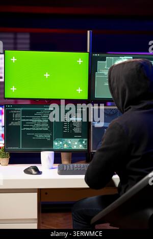 Hacker using green screen PC to gain unauthorized network access, targeting unpatched connections. Man using mockup computer to bypass security and exploit servers for stolen data profit. Stock Photo