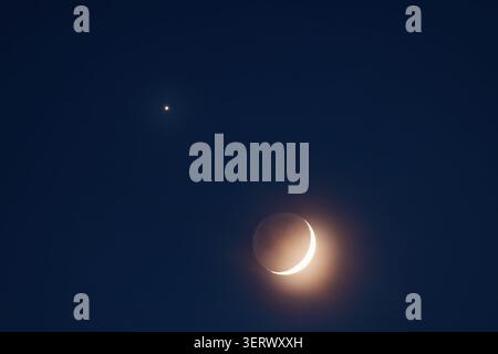 Crescent moon with planet shining in the dark blue night sky in Punta Cana Stock Photo