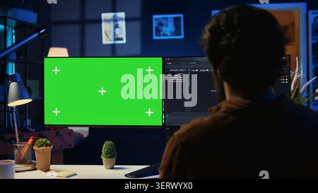 Freelancing man doing IT support job from apartment personal office, coding on isolated screen PC, software programmer writing lines of code on chroma key computer at home. Stock Photo