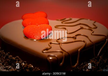 Heart-shaped chocolate cake with red hearts on red background Stock Photo