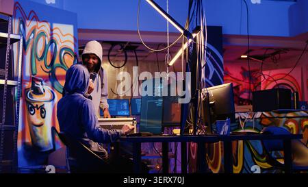 Hacker arriving in secret underground base with SSD containing data obtained from victim after tricking it into installing ransomware program they developed, men happy with their criminal plan. Stock Photo