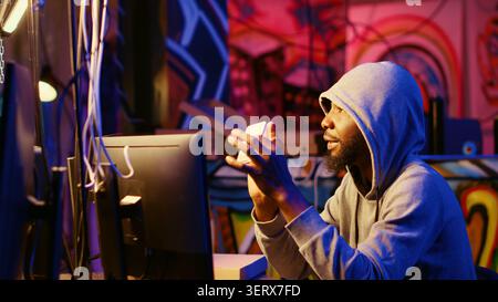 Hacker holding SSD device with valuable information after doing data breaches and financial theft, cybercriminal with gathered users bank account credentials ready to sell it on black market. Stock Photo