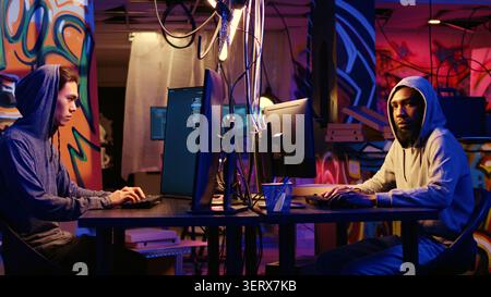 Portrait of security hackers exploring methods of breaching defenses and exploiting weaknesses in computer networks, malicious programmers in basement getting past firewalls. Stock Photo