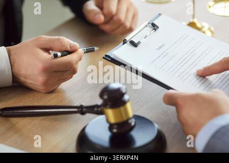 Client reviewing document before signing it, during formal meeting with lawyer Stock Photo