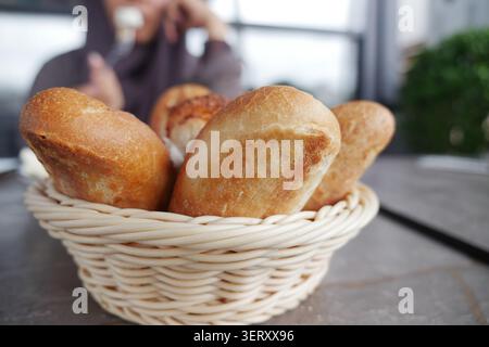 Fresh bread rolls in a basket on a table Stock Photo