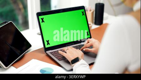 Laptop, green screen and hands in home for accounting, website and business research at desk. Remote work, mockup space and person with tech for Stock Photo
