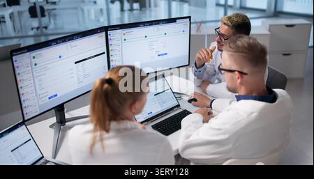 Healthcare Team Reviews Medical Billing Data On Laptops For Training. Stock Photo