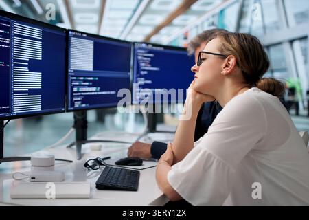 Frustrated Developers Working Late On Broken Code In Quiet Office Space. Stock Photo