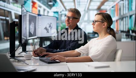 Two Engineers Use CAD Software To Design A Detailed 3D Car Gearbox. Stock Photo