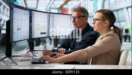 Two Office Workers Analyze Digital Document Workflow System On Computer Screen. Stock Photo