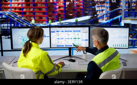 Two Workers Analyze Ecommerce Software On Multiple Screens For Efficient Delivery. Stock Photo