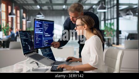 Two Software Engineers Working Together On Secure Code At Office Desk. Stock Photo