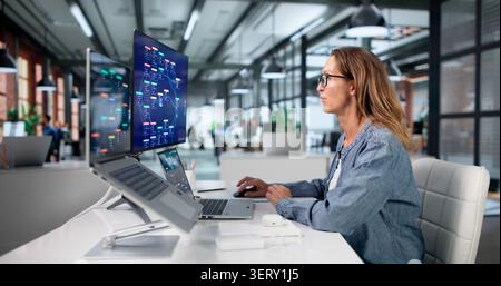 Mature Woman Uses Low Code Laptop Software To Build Workflow Automation. Stock Photo