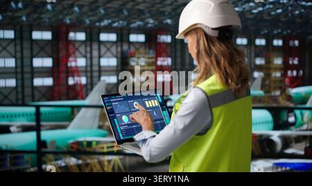Experienced Female Engineer Uses Laptop To Inspect Aerospace Engine Parts. Stock Photo