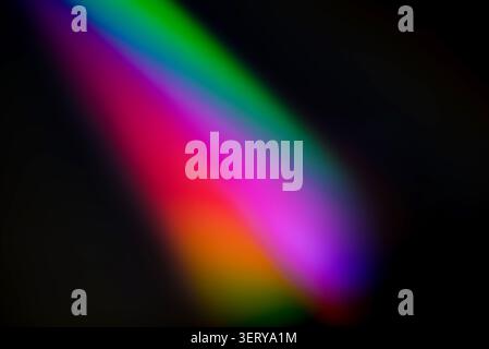 Abstract rainbow light leak on dark background. Colorful lens flare effect with soft glow and diagonal spectrum beam for photo overlays. Stock Photo