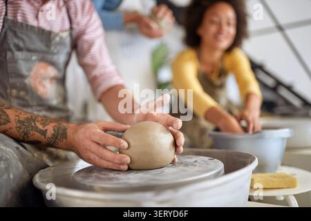 close up of male student  hands holding clay on wheel at pottery workshop . Creative, hobby ,activities concept Stock Photo
