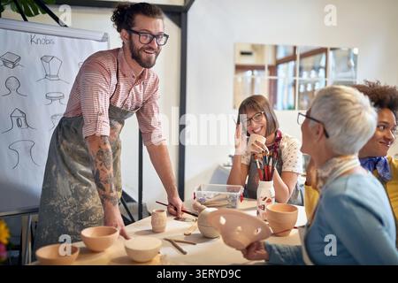 happy group of people making pots from clay at a pottery studio. Creative, hobby ,activities concept Stock Photo