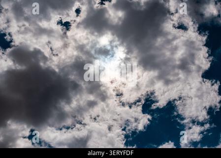 Dramatic sun breaking through dark, heavy storm clouds. Ethereal light of the sun behind dramatic stormy cloud formations. Stock Photo