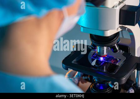 Scientist Examining Sample Through Microscope in Modern Laboratory Stock Photo