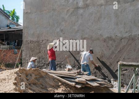 Construction workers plastering a high concrete building wall Stock Photo