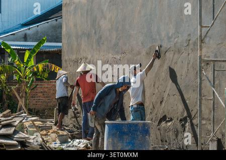 Construction workers plastering a high concrete building wall Stock Photo