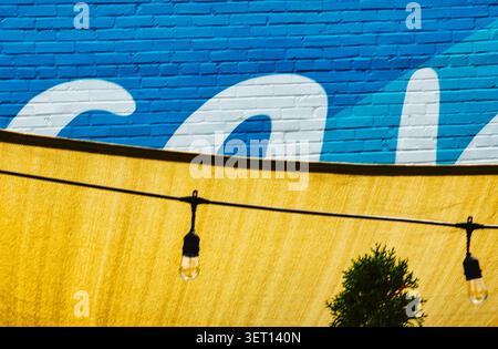 Brilliantly blue wall behind a yellow fabric awning with a string of lights Stock Photo