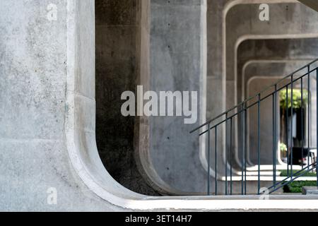 A striking shot of raw concrete brutalist architecture featuring a perspective view of repeating rounded rectangular arches. The composition includes Stock Photo