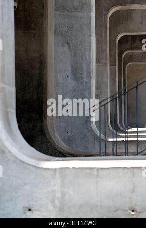 A striking shot of raw concrete brutalist architecture featuring a perspective view of repeating rounded rectangular arches. The composition includes Stock Photo