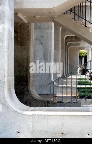 A heavy concrete architectural structures, featuring repeating geometric arches that create a tunnel perspective alongside a minimalist outdoor stairc Stock Photo