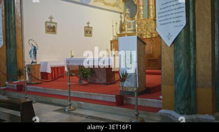 Church interior with soft defocused altar and red carpeted chancel, shallow blur on columns and ropes; background backplate copyspace calm. Stock Photo