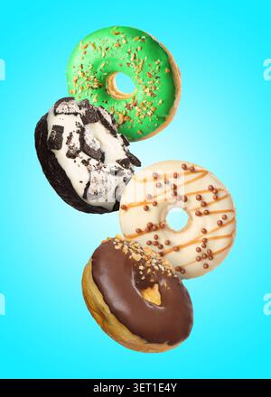 Tasty donuts covered with icing falling on light blue background Stock Photo