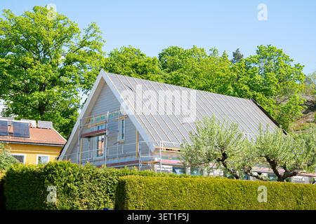 Home improvement and renovation concept with scaffolding around house with work being done on the roof in summer Stock Photo