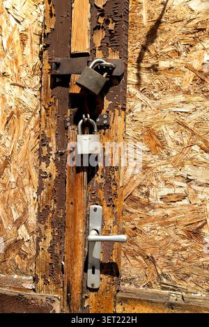 Weathered wooden door with rusty padlocks Stock Photo