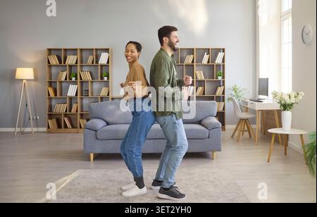 Happy couple dancing at home in cozy living room, playful lifestyle concept Stock Photo