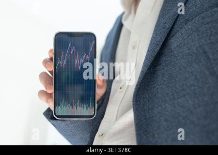 Close-up of a businessman holding a smartphone displaying a stock market chart Stock Photo