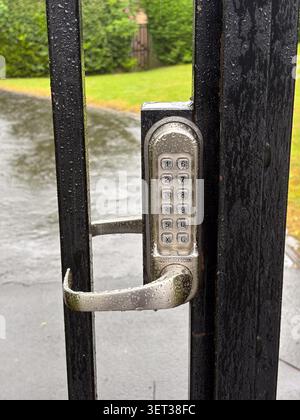 Code lock on a black metal gate, rainy day, courtyard entrance Stock Photo