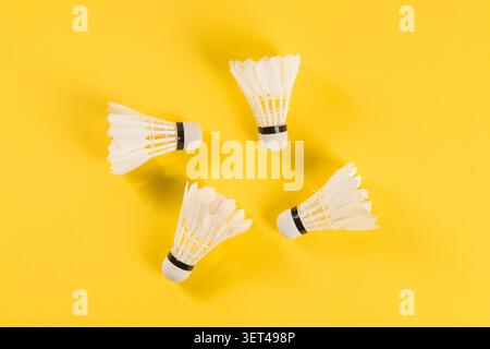 White badminton shuttlecocks with feathers arranged on a bright yellow background Stock Photo