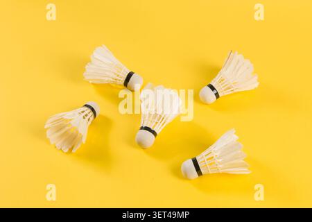 Badminton shuttlecocks lying on a bright yellow surface ready for play Stock Photo