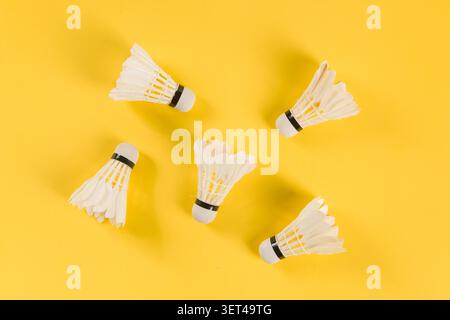 Badminton shuttlecocks lying on a bright yellow surface ready for play Stock Photo