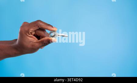 Hand Holding Key, Unrecognizable Person, Blue Background, Security Concept Stock Photo