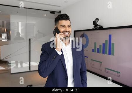 Confident businessman talking on phone in office Stock Photo