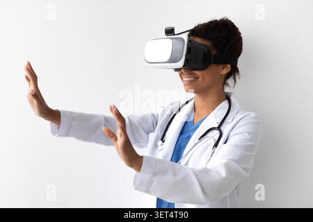 Smiling Black Female Doctor Using Vr Headset In Clinic, Engaging In Virtual Reality Treatment Stock Photo