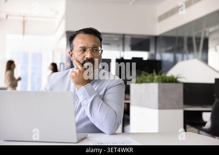 Thoughtful businessman working at office desk with laptop Stock Photo