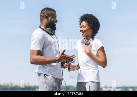 African American Woman Discussing Jogging Program With Coach Outside Stock Photo