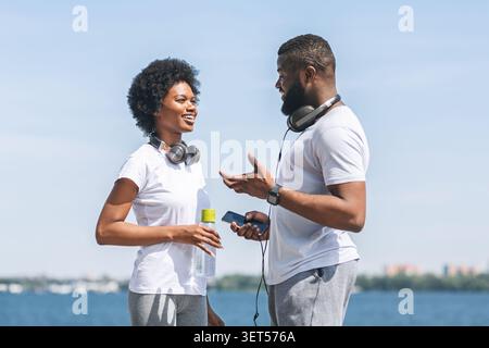 Afro Couple Chatting Before Morning Run Along River Embankment Stock Photo
