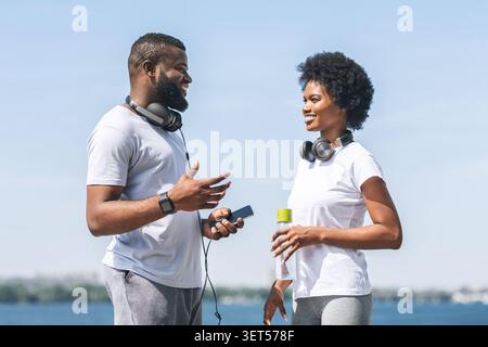 Black Couple Talking Before Morning Jog Along River Bank Stock Photo